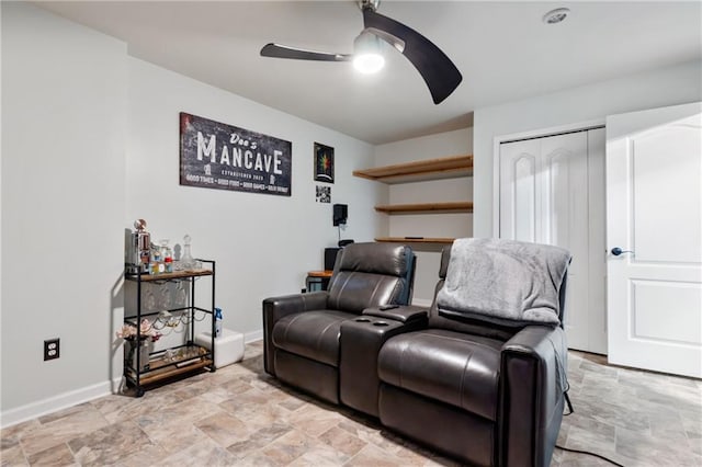 home theater with a ceiling fan, baseboards, and stone finish floor