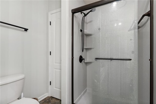 full bathroom featuring baseboards, a shower stall, and toilet
