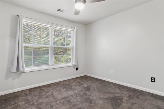 empty room with baseboards, a ceiling fan, dark colored carpet, and visible vents