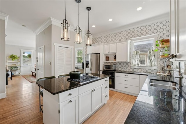 218 S Ave SE, Atlanta, GA 30315 - kitchen featuring appliances with stainless steel finishes, ornamental molding, white cabinets, light wood-style floors, and a center island