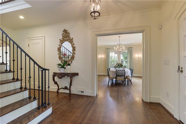 entryway with an inviting chandelier, crown molding, and dark hardwood / wood-style floors