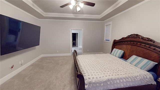 carpeted bedroom with a tray ceiling, ceiling fan, and ornamental molding