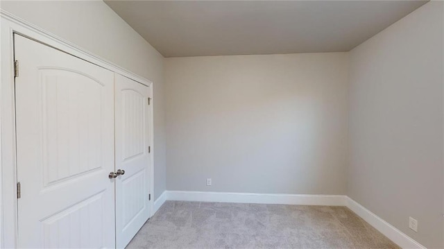 unfurnished bedroom with light carpet and a closet