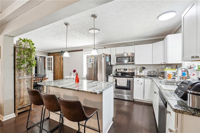 kitchen with stainless steel appliances, light stone countertops, dark wood-style floors, and a center island