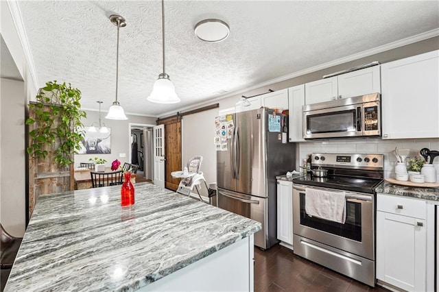 kitchen with light stone counters, ornamental molding, stainless steel appliances, a barn door, and backsplash