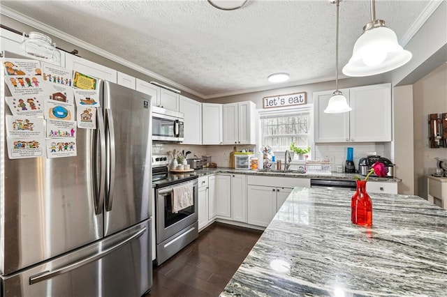 kitchen with light stone countertops, dark wood-style flooring, stainless steel appliances, white cabinets, and crown molding