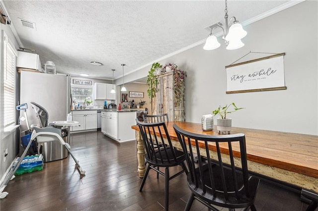 dining room with visible vents, dark wood-type flooring, a chandelier, and a textured ceiling