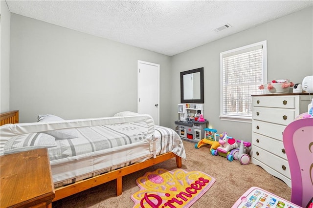 bedroom with visible vents, carpet floors, and a textured ceiling