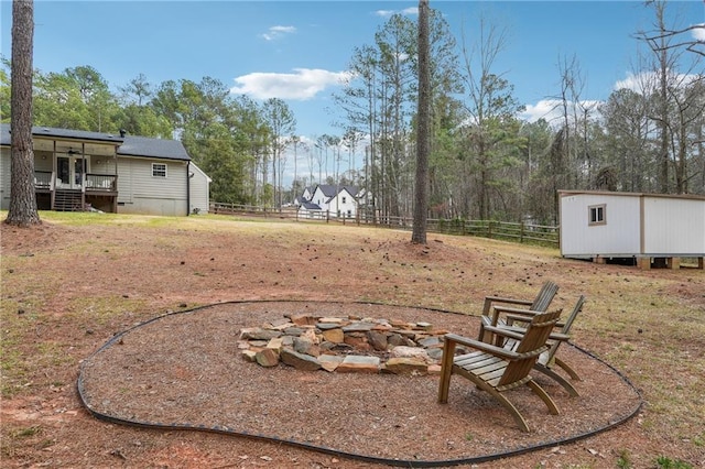 view of yard with an outdoor structure, a fire pit, and fence