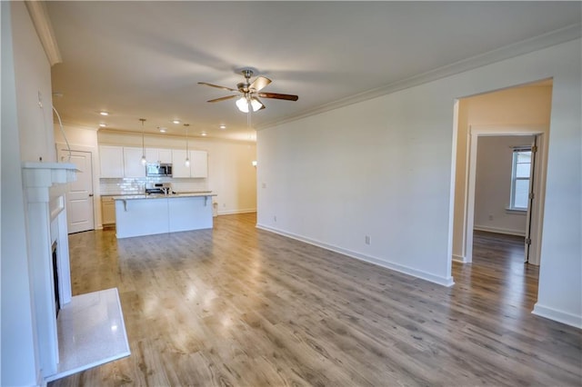 2929 Rambler Dr, Loganville, GA 30052 - unfurnished living room with ornamental molding, ceiling fan, baseboards, light wood-style floors, and a fireplace