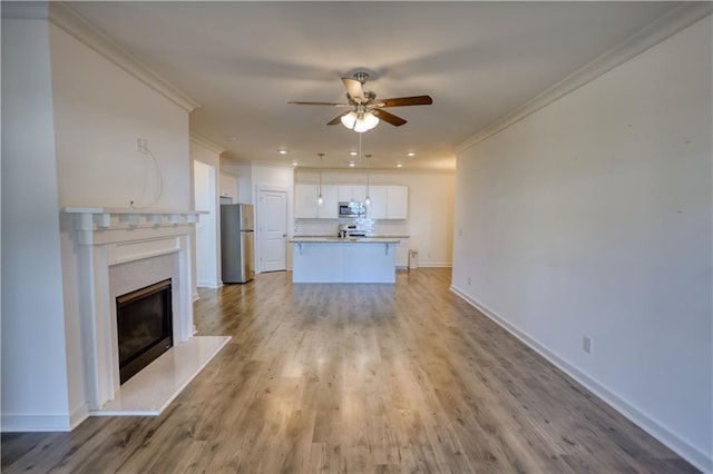 2929 Rambler Dr, Loganville, GA 30052 - unfurnished living room featuring a ceiling fan, crown molding, a premium fireplace, light wood-style flooring, and baseboards