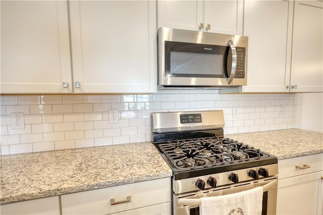2929 Rambler Dr, Loganville, GA 30052 - kitchen with appliances with stainless steel finishes, decorative backsplash, light stone countertops, and white cabinetry
