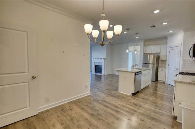 2929 Rambler Dr, Loganville, GA 30052 - kitchen with crown molding, stainless steel appliances, a chandelier, a center island with sink, and decorative backsplash