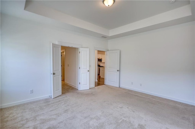 2929 Rambler Dr, Loganville, GA 30052 - unfurnished bedroom with a tray ceiling, carpet, and baseboards