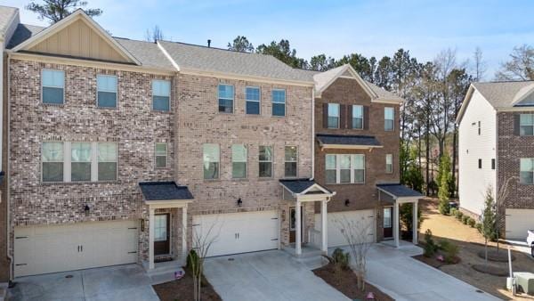 townhome / multi-family property featuring board and batten siding, a garage, driveway, and brick siding