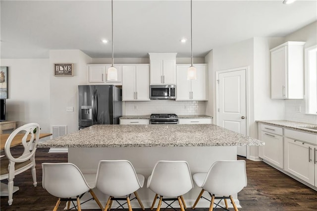 kitchen with a kitchen bar, a center island, backsplash, and stainless steel appliances