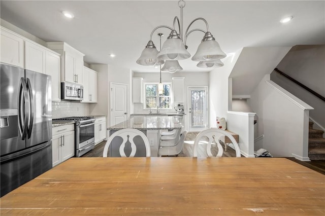 kitchen with a center island, appliances with stainless steel finishes, white cabinetry, and backsplash