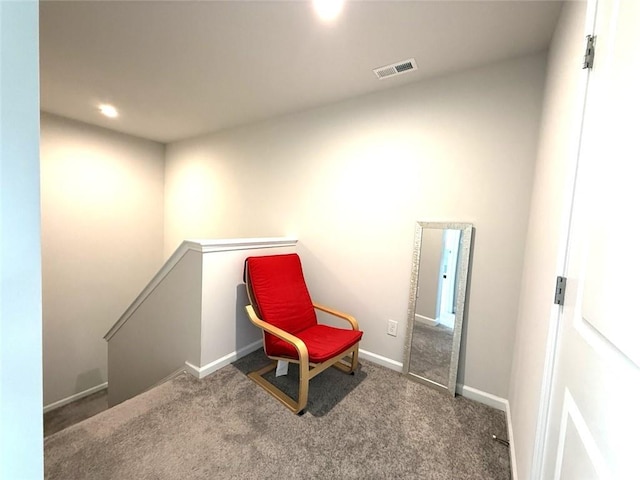 sitting room with an upstairs landing, visible vents, baseboards, and carpet floors