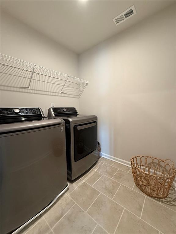 laundry room with visible vents, baseboards, separate washer and dryer, laundry area, and light tile patterned flooring