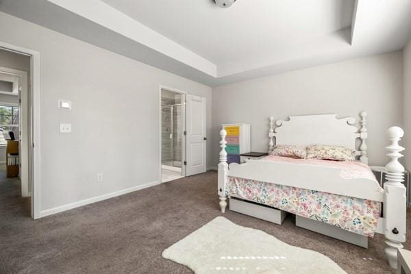 carpeted bedroom featuring ensuite bathroom, baseboards, and a raised ceiling