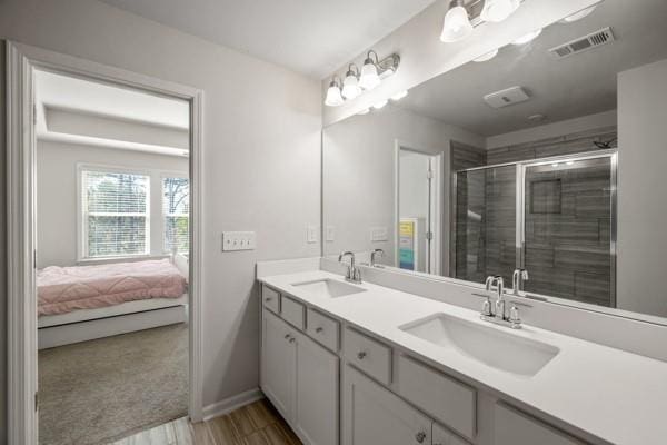 bathroom with a sink, visible vents, a shower stall, and double vanity