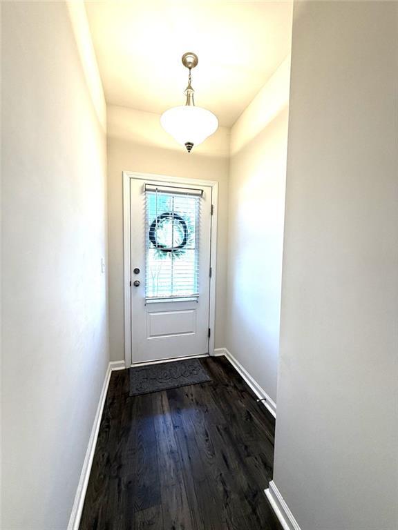 entryway with dark wood-style flooring and baseboards
