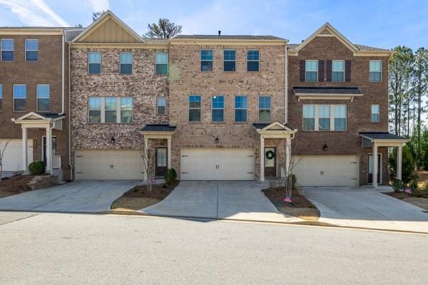 multi unit property with brick siding, a garage, and concrete driveway