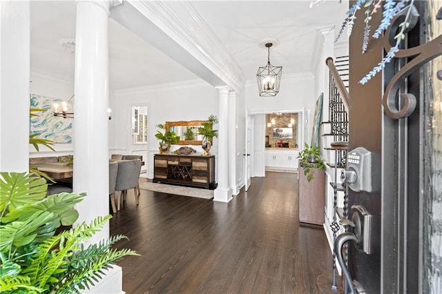 entryway with an inviting chandelier, dark hardwood / wood-style flooring, crown molding, and decorative columns