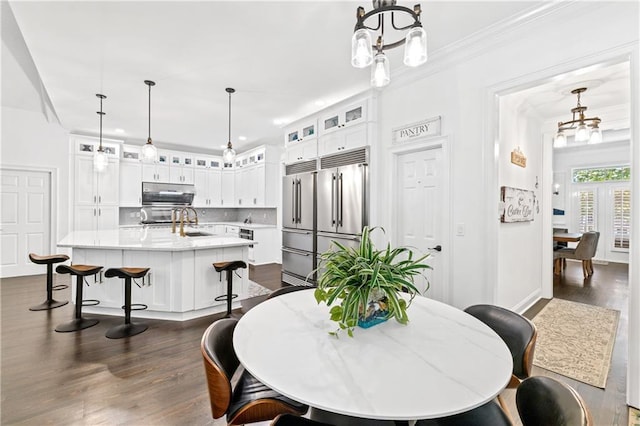 dining space featuring dark hardwood / wood-style flooring, ornamental molding, and sink