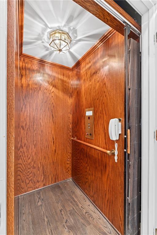 interior space featuring wooden walls, wood-type flooring, and elevator