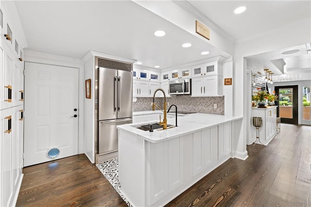 kitchen featuring sink, kitchen peninsula, tasteful backsplash, white cabinetry, and stainless steel appliances