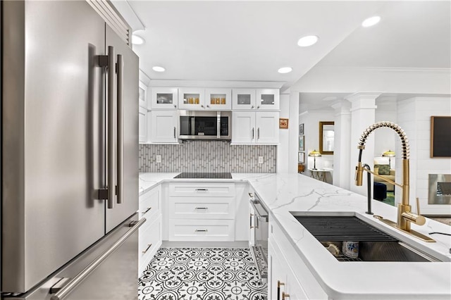 kitchen with sink, stainless steel appliances, backsplash, kitchen peninsula, and white cabinets