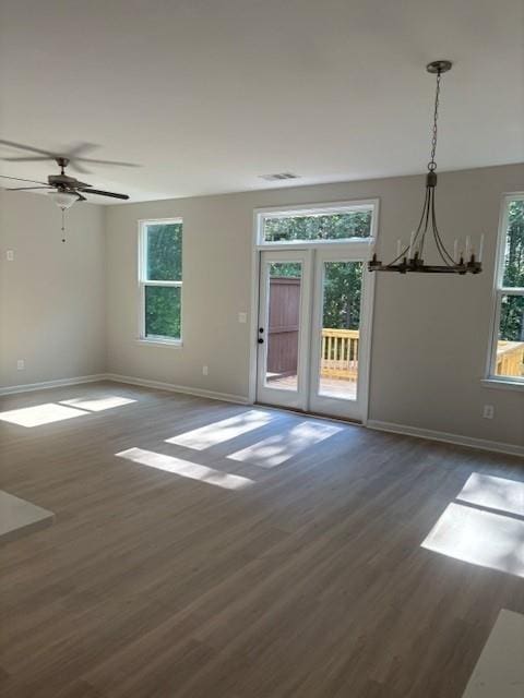 unfurnished room with ceiling fan with notable chandelier, dark wood-type flooring, and french doors