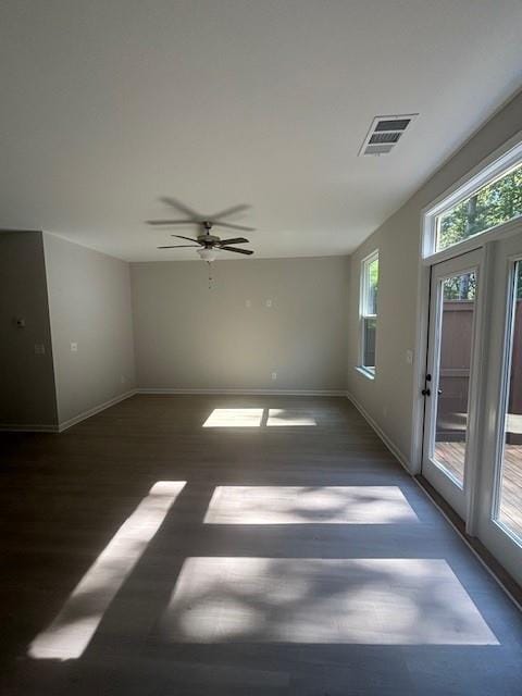 spare room featuring a wealth of natural light, ceiling fan, and dark hardwood / wood-style floors