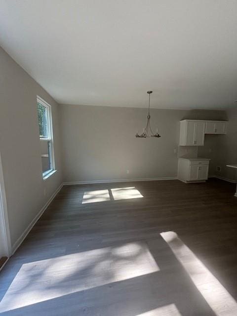 unfurnished living room featuring dark hardwood / wood-style flooring and a notable chandelier