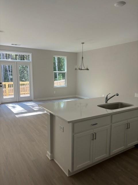 kitchen with a wealth of natural light, sink, pendant lighting, a notable chandelier, and white cabinets