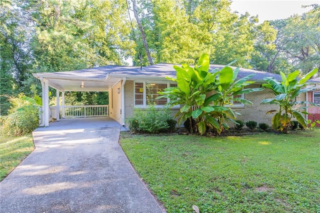 exterior space featuring brick siding, an attached carport, concrete driveway, and a front lawn