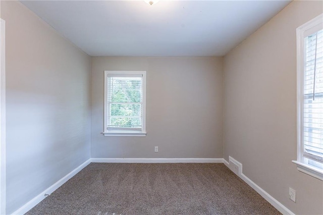 spare room with carpet, visible vents, and baseboards