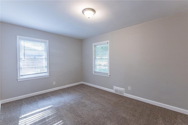 carpeted spare room with baseboards, visible vents, and a wealth of natural light