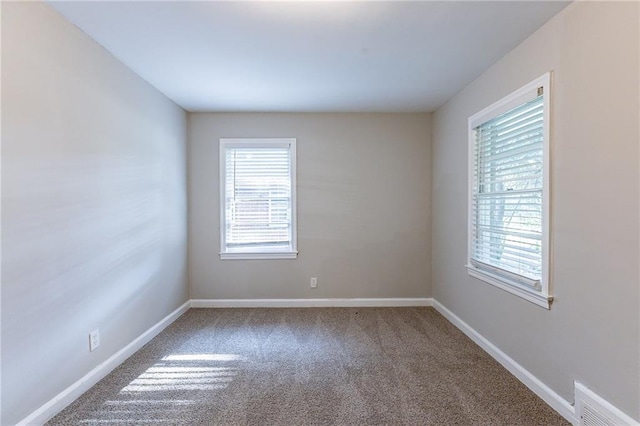 carpeted spare room with visible vents, plenty of natural light, and baseboards