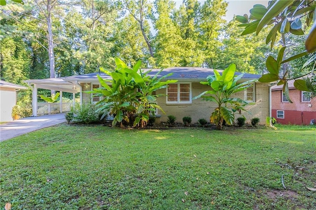 view of front facade featuring an attached carport, brick siding, concrete driveway, and a front yard