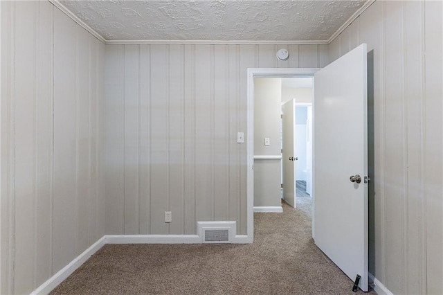 empty room featuring carpet flooring, a textured ceiling, and visible vents