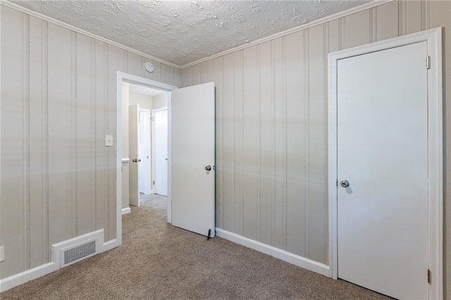 unfurnished bedroom with visible vents, a textured ceiling, and carpet