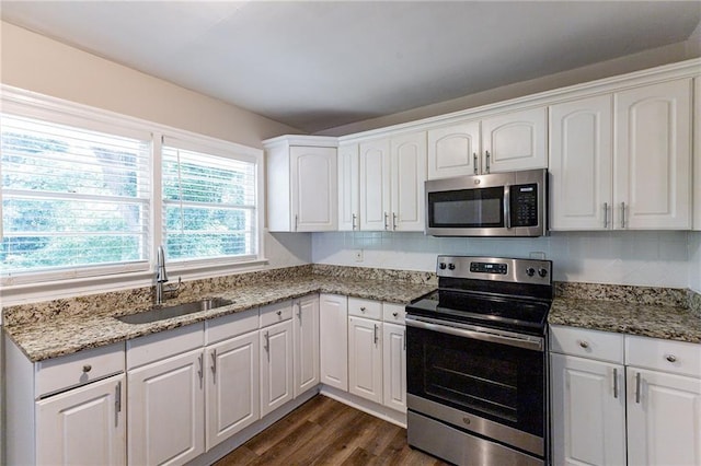 kitchen with light stone counters, dark wood-style flooring, a sink, stainless steel appliances, and white cabinetry