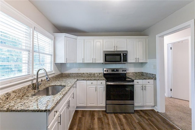 kitchen featuring light stone countertops, white cabinetry, stainless steel appliances, and a sink