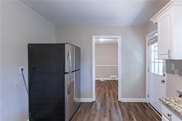 kitchen with visible vents, dark wood-type flooring, white cabinetry, freestanding refrigerator, and baseboards