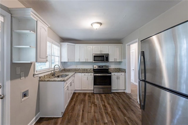 kitchen featuring a sink, open shelves, stainless steel appliances, dark stone counters, and white cabinets