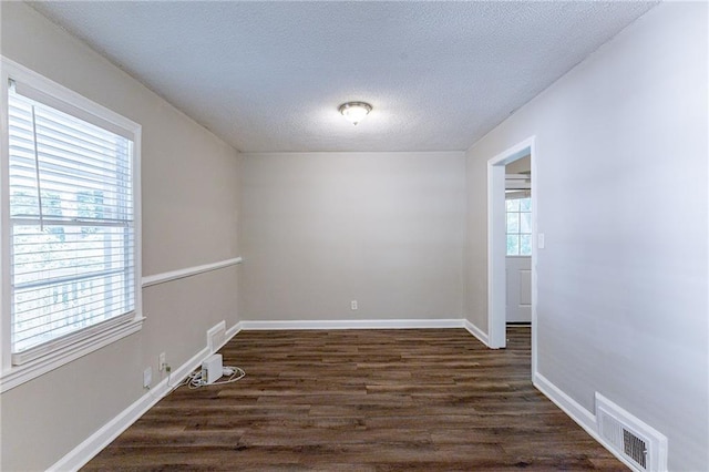 unfurnished room with visible vents, baseboards, a textured ceiling, and dark wood-style floors