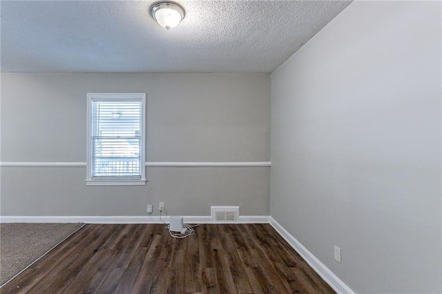 spare room with visible vents, baseboards, a textured ceiling, and wood finished floors