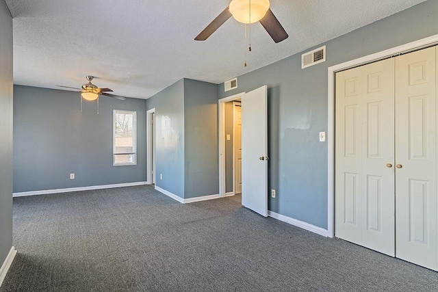 unfurnished room with ceiling fan, dark carpet, and a textured ceiling